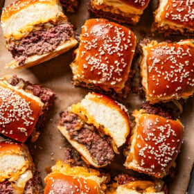 Cheeseburger sliders arranged on a sheet pan lined with parchment paper.