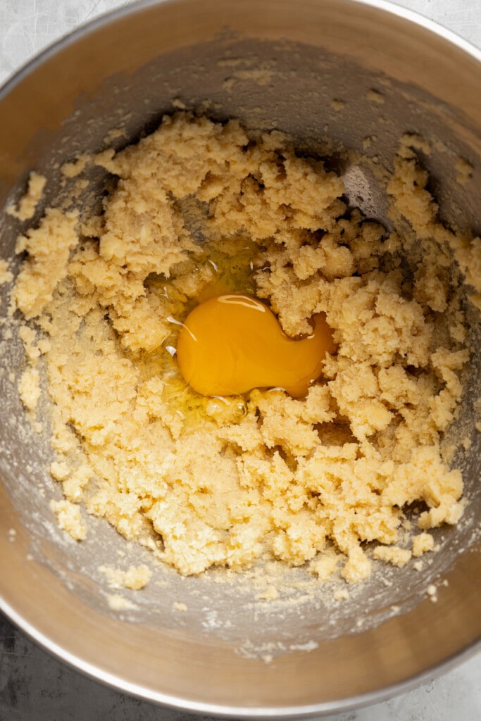 Adding an egg to creamed butter and brown sugar.