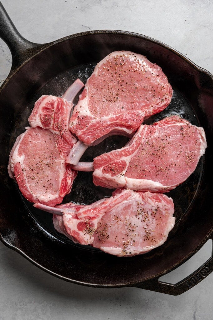 Searing pork chops in a cast iron pan.