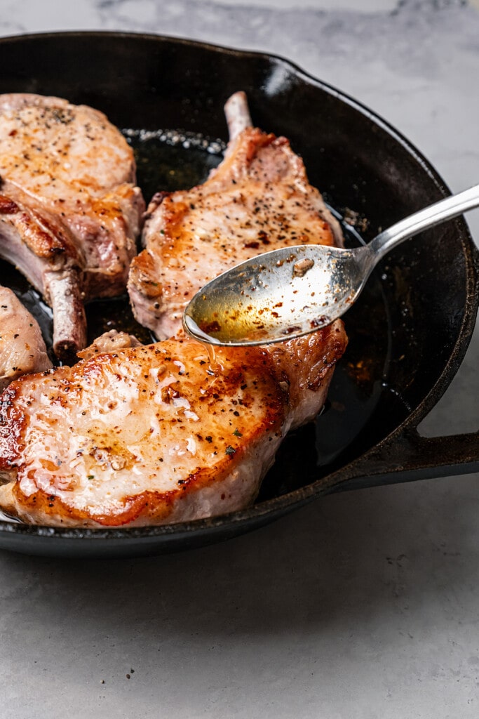 Basting pork chops with butter.