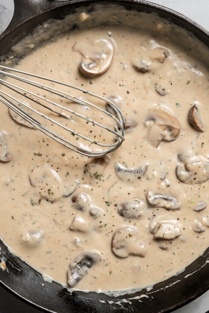Whisking milk and cream of mushroom soup into a roux with sauteed mushrooms.