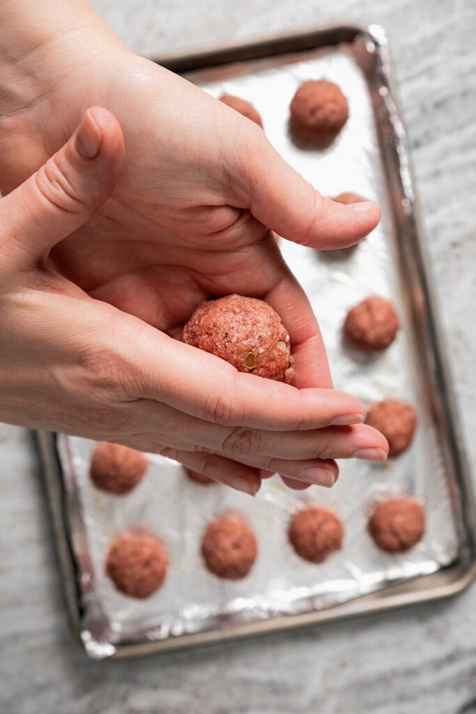 Forming a mixture of ground beef, Panko, eggs, and seasonings into meatballs.
