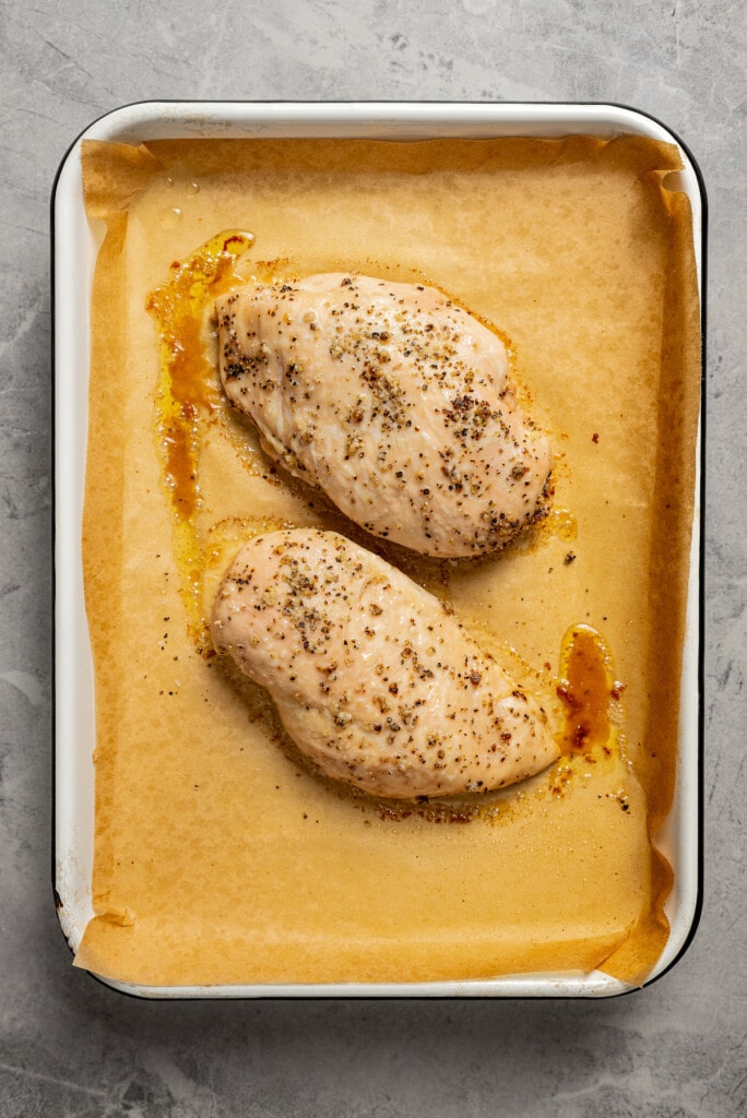Roasted chicken breasts on a baking sheet lined with parchment paper.