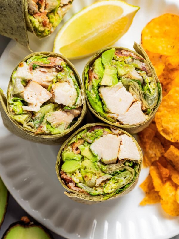 Closeup overhead image of chicken Caesar wraps on a plate with chips.