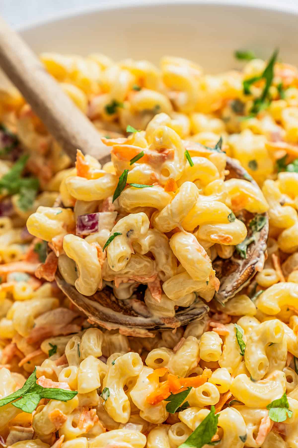 Scooping up Hawaiian mac salad with a wooden spoon.