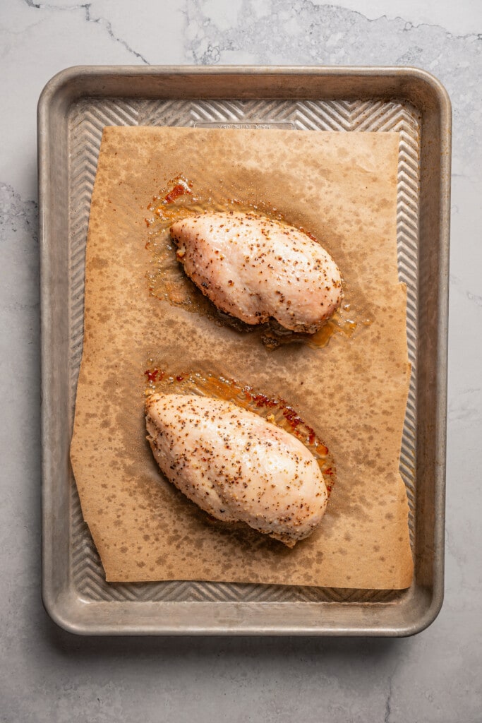 2 roasted chicken breasts on a sheet pan.