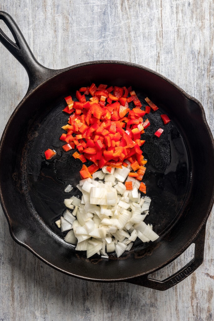 Adding chopped onion and red bell pepper to a skillet.