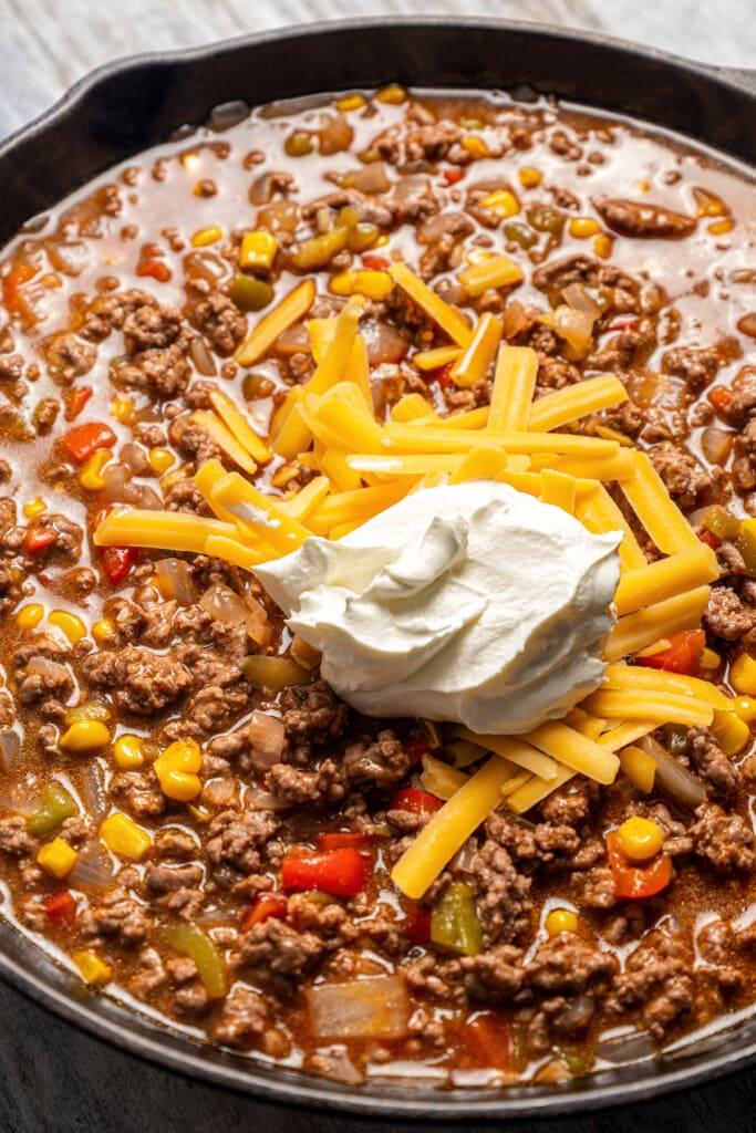 Stirring cheddar cheese and sour cream into tamale pie filling.