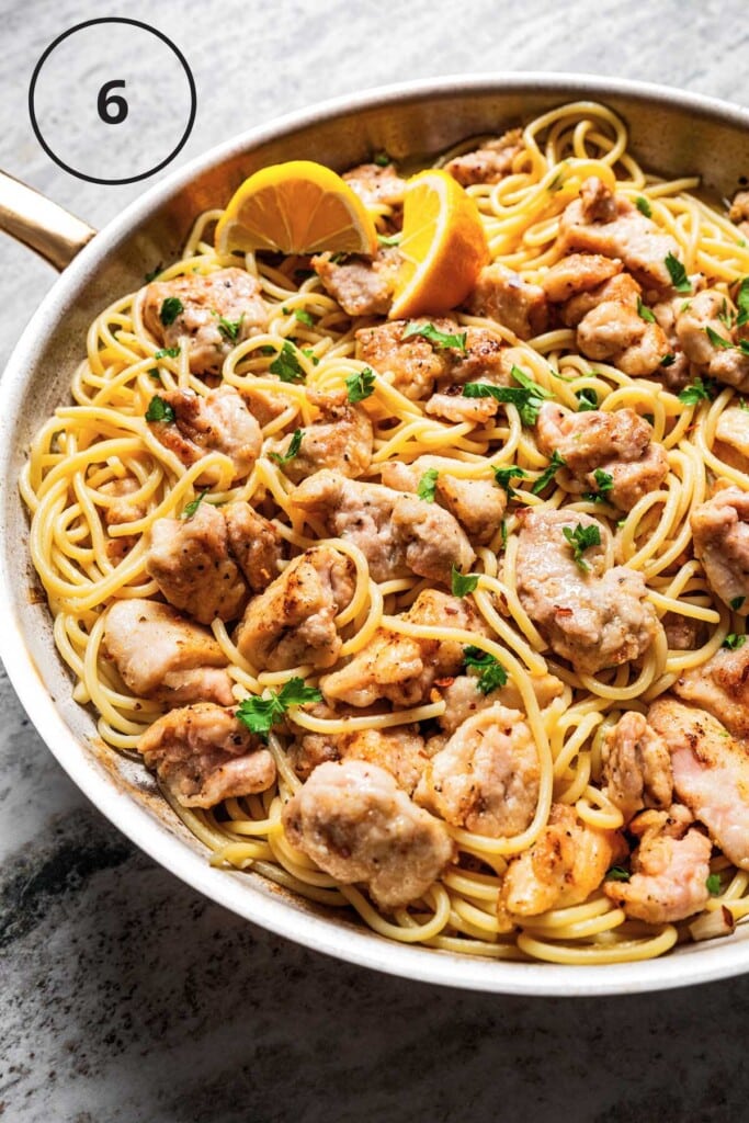 Spaghetti topped with bite-sized chicken pieces.