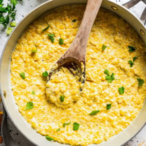 Stirring through corn in a skillet with cream and butter.