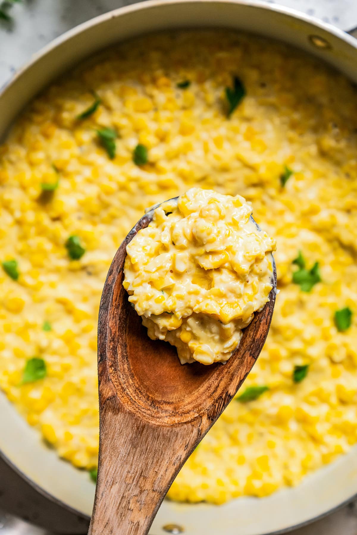 A wooden spoon holding up creamed corn.