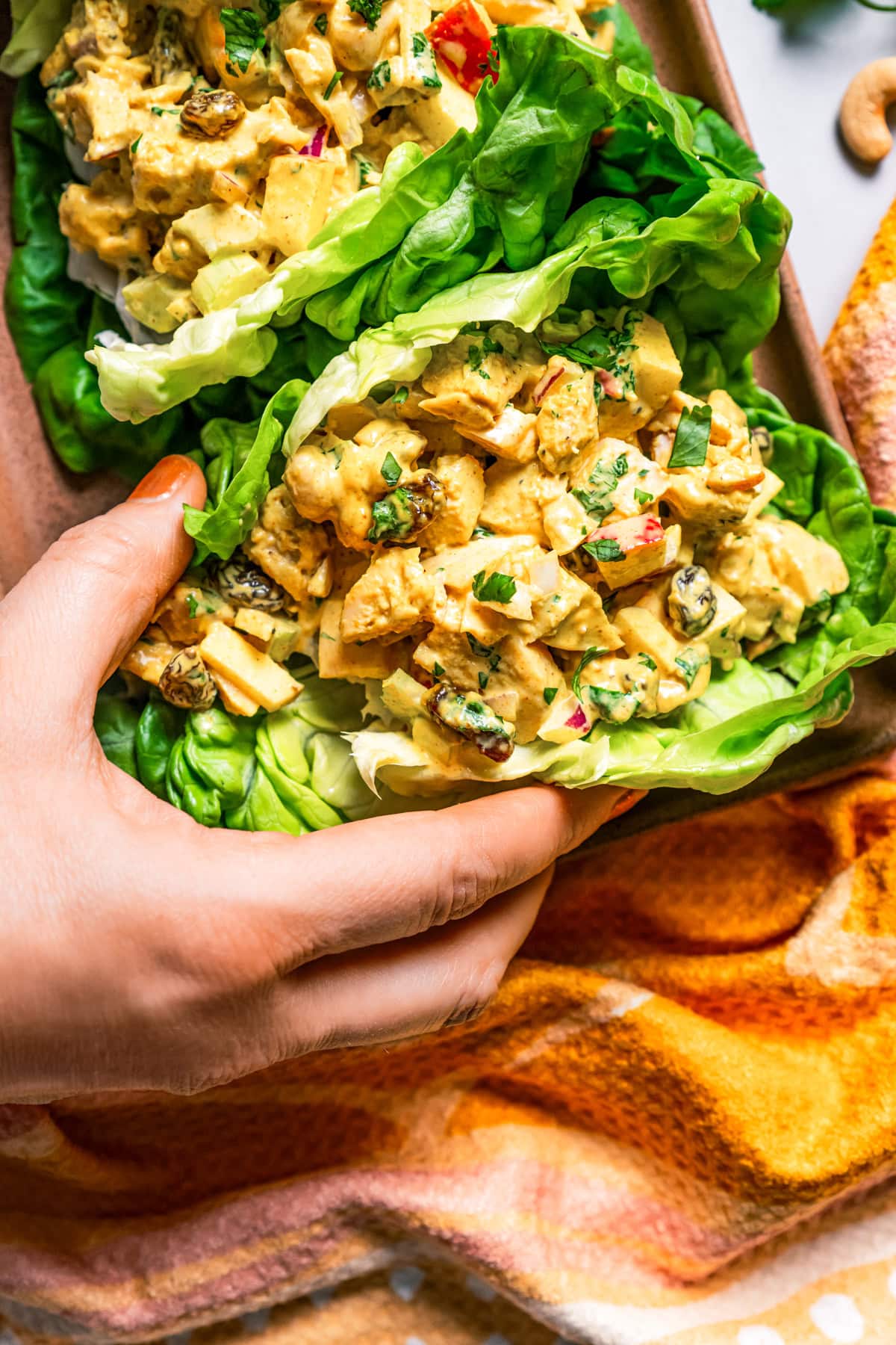 A hand picking up a curry chicken salad lettuce wrap.