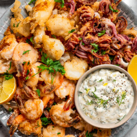 Fritto misto served on a round plate with a small bowl of tartar sauce.