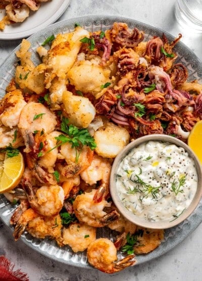 Fritto misto served on a round plate with a small bowl of tartar sauce.