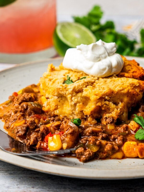 A slice of tamale pie on a plate with a dollop of sour cream on top.