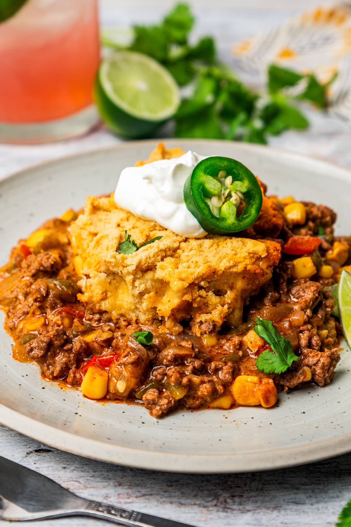 A slice of tamale pie on a plate with a dollop of sour cream on top.