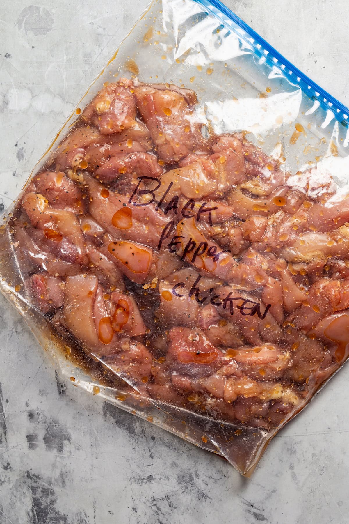 Chicken pieces marinating inside a gallon freezer bag.