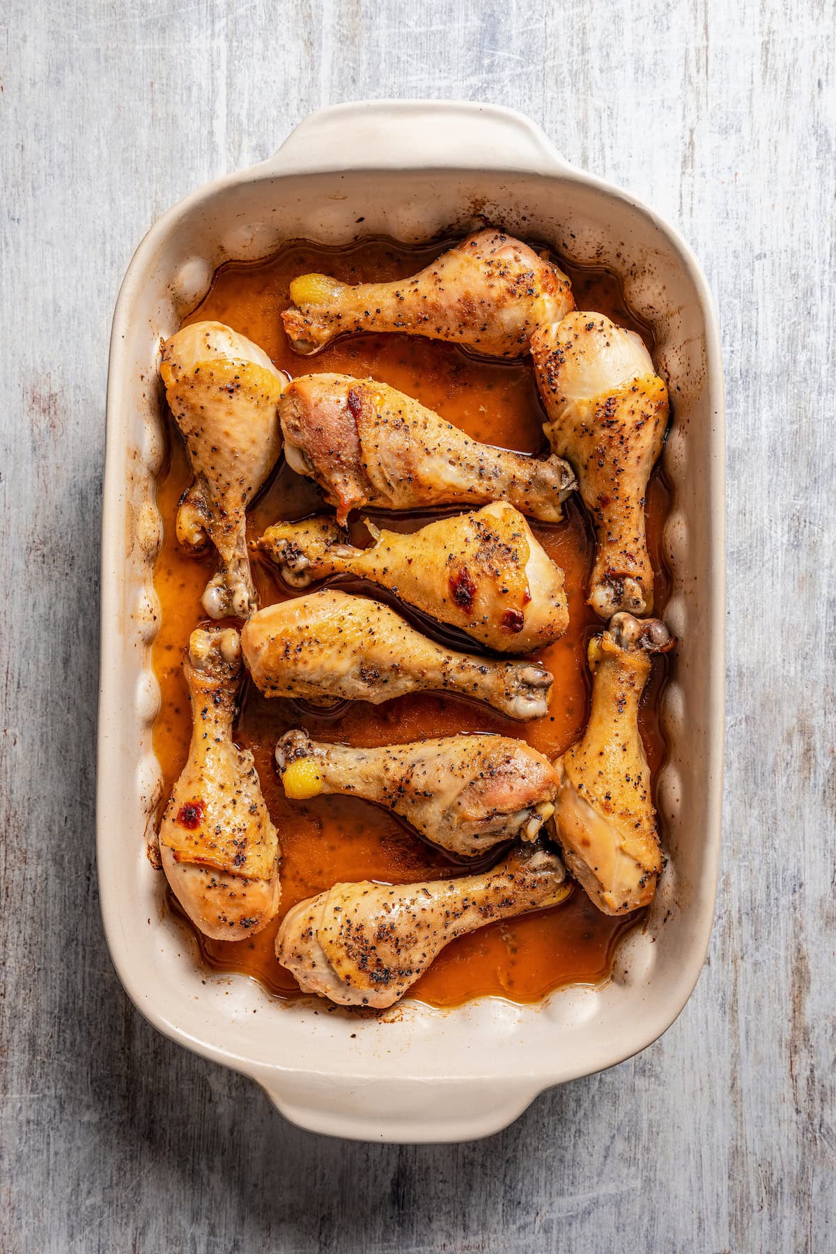 Baked honey soy chicken drumsticks in a ceramic baking dish.