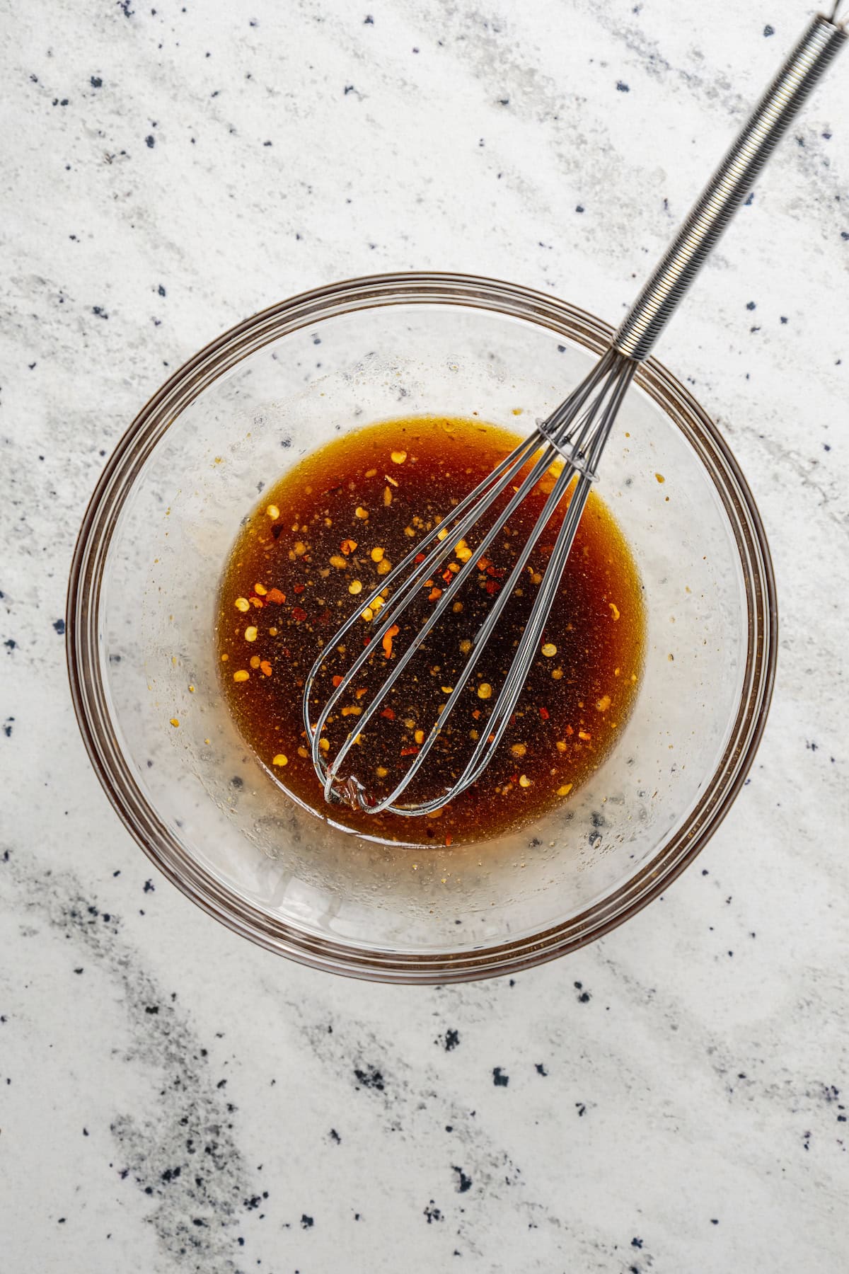 Seasoning sauce in a glass bowl with a whisk.