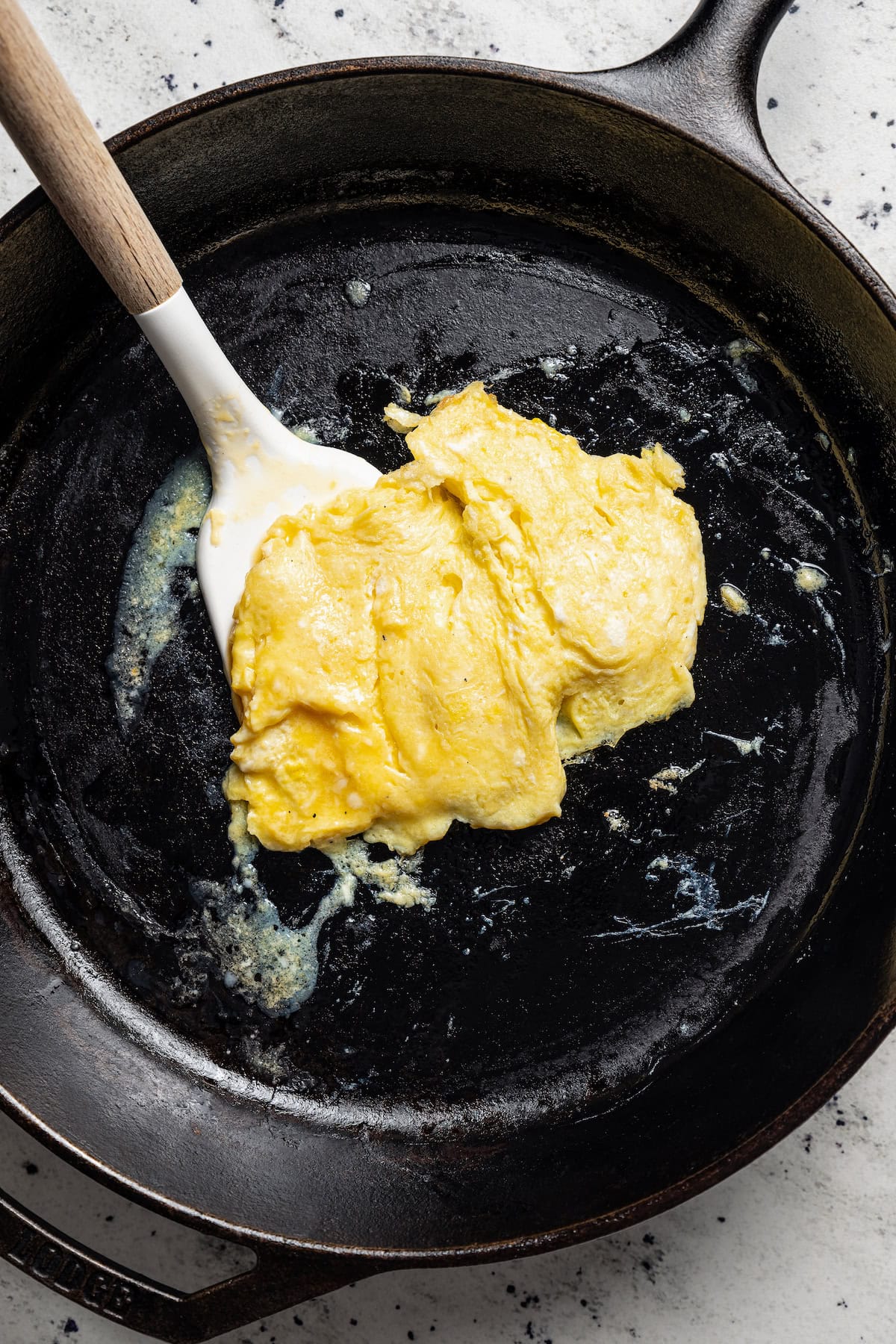 A scrambled egg in a skillet with a spatula.