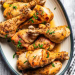 Overhead view of honey soy chicken drumsticks arranged on a white oval platter with a blue rim.