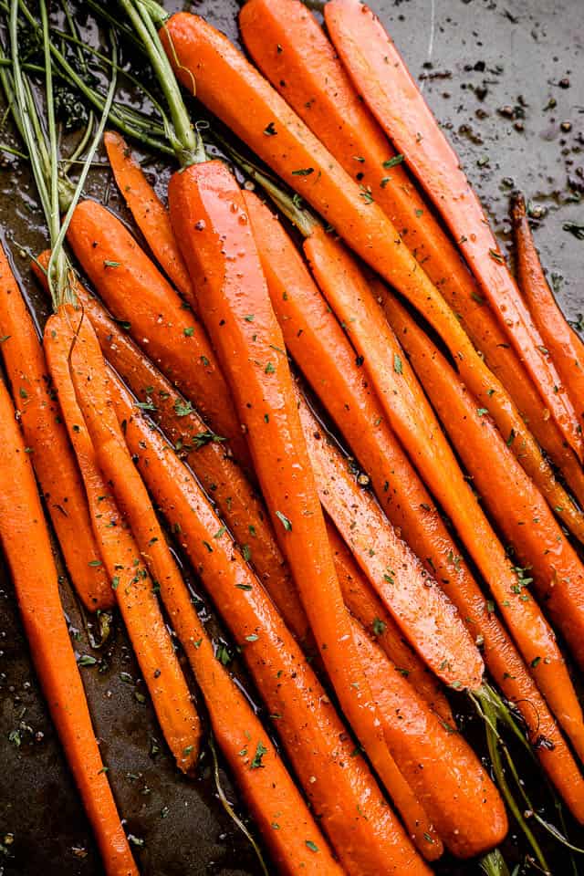 A bunch of carrots arranged on a sheet pan.
