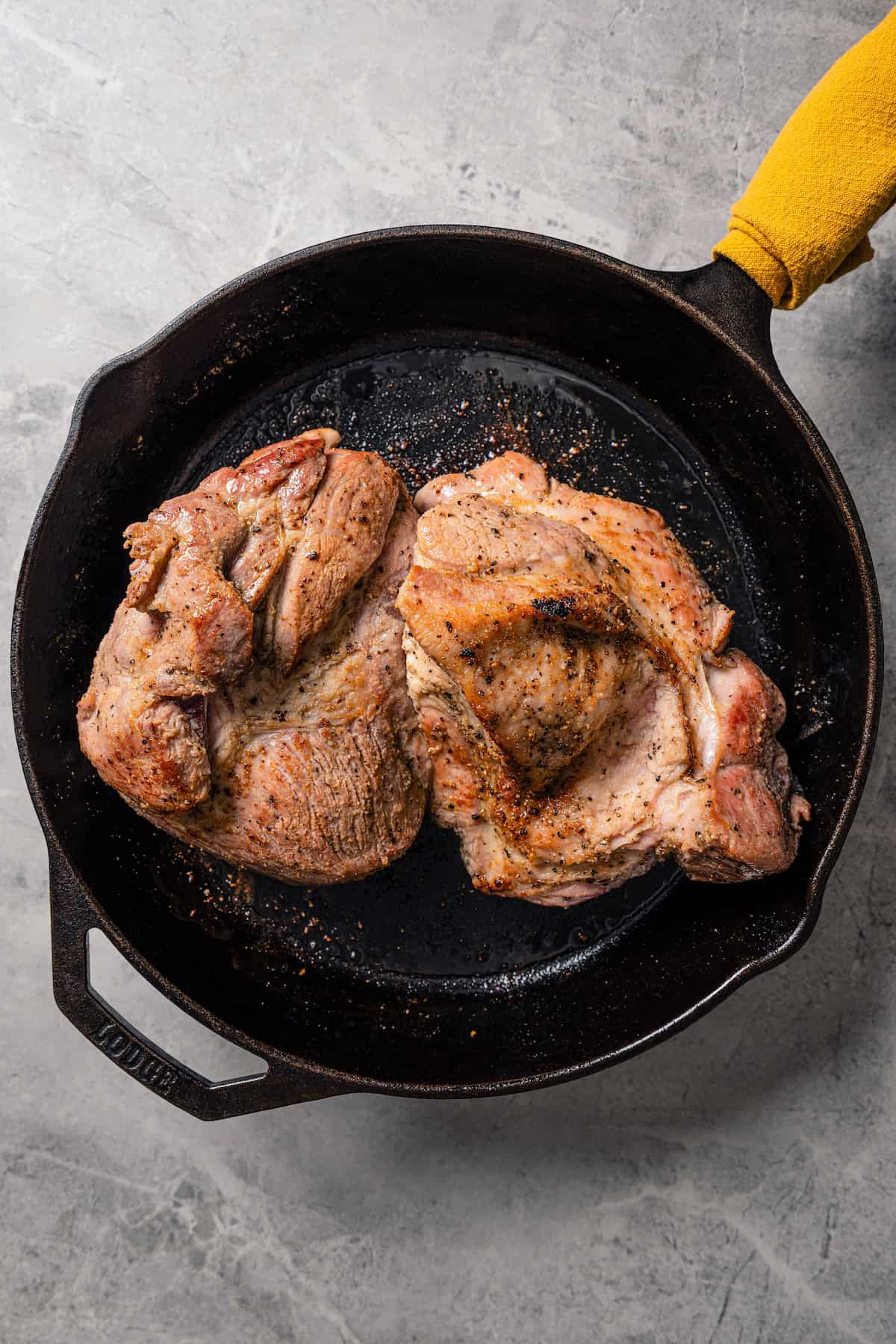 Browned seasoned pork roast in a skillet.