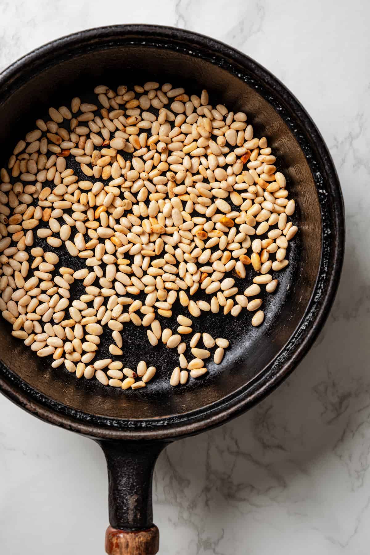 Pine nuts toasting in a skillet.