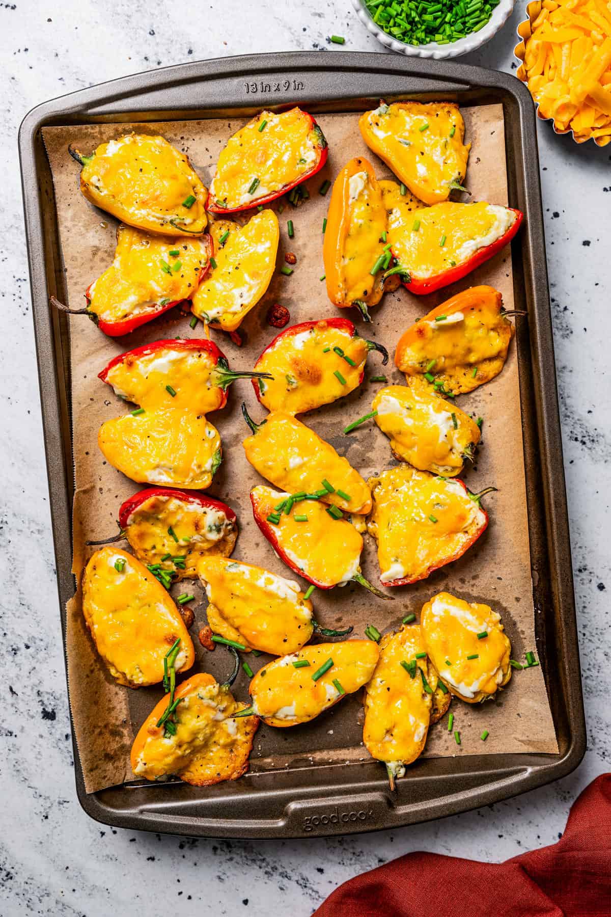 Baked cream cheese stuffed peppers on a lined baking sheet.