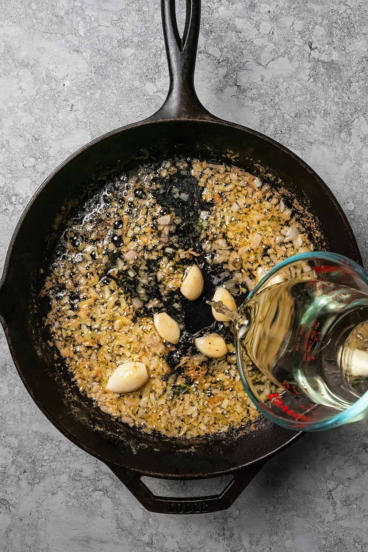 White wine is used to deglaze a cast iron pan with sauteed shallots and other pan sauce ingredients.