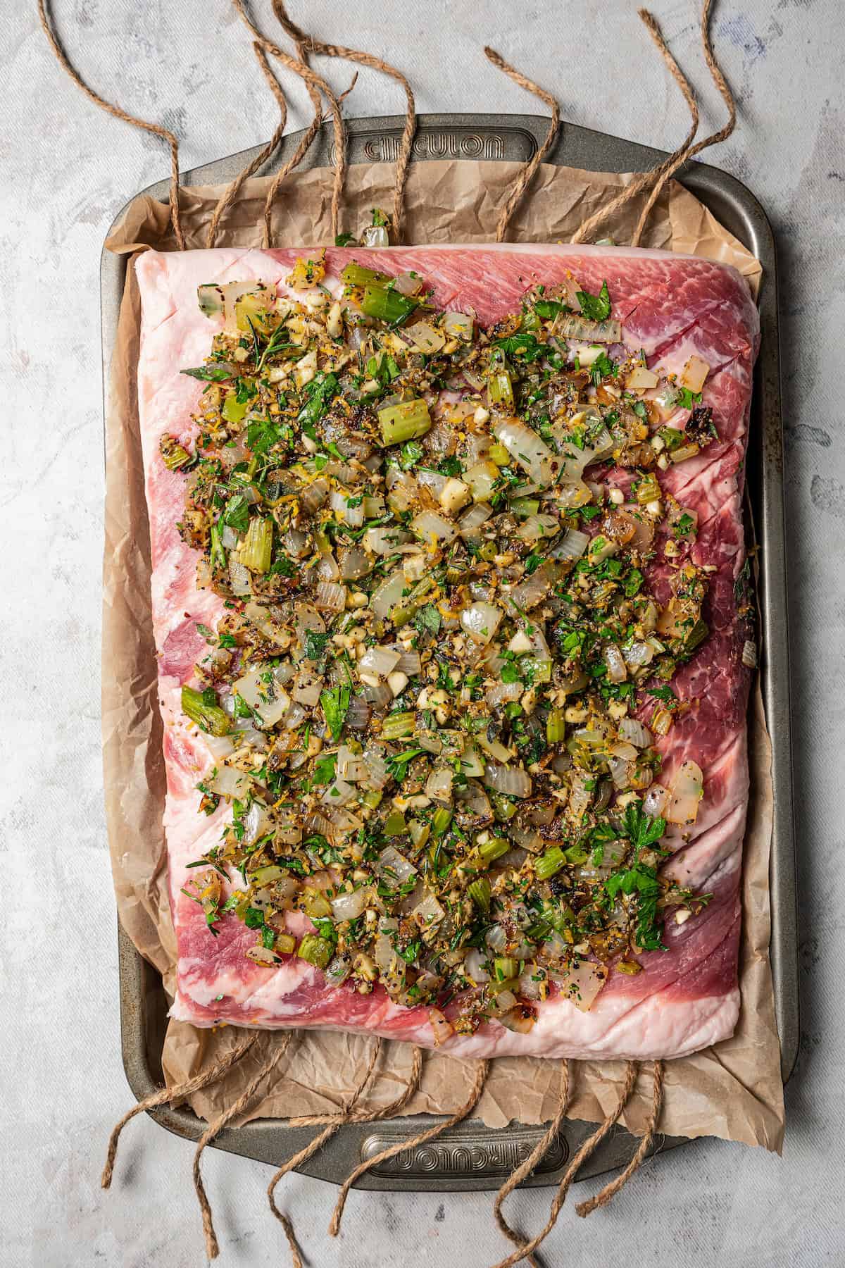 Seasoning mix spread over a flat pork belly on a baking sheet.