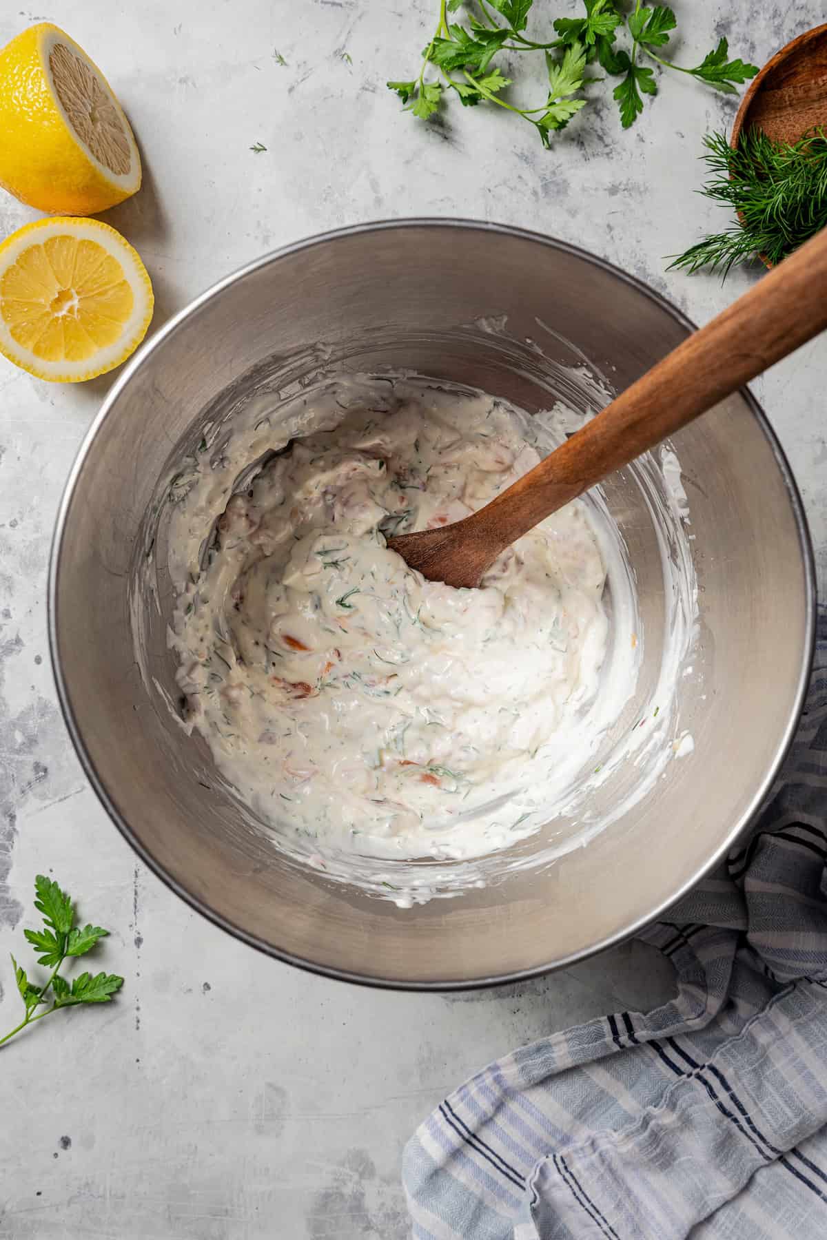 Smoked salmon dip combined in a metal mixing bowl with a wooden spoon.