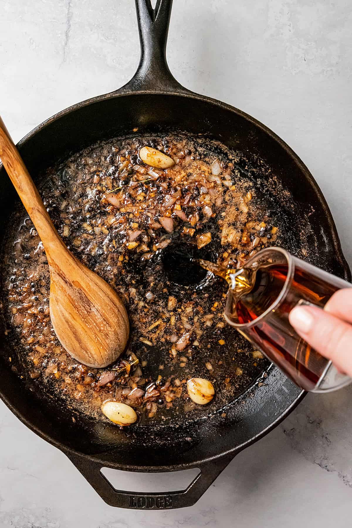 Red wine being poured into a skillet to deglaze.