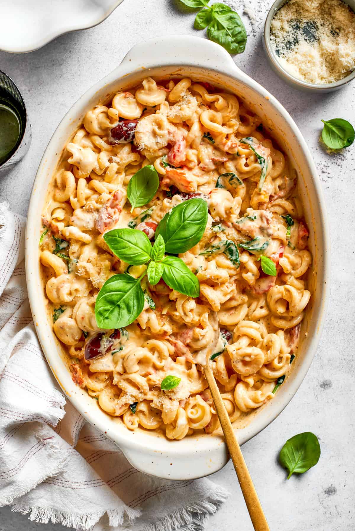 Baked pasta in a baking dish garnished with fresh basil leaves.