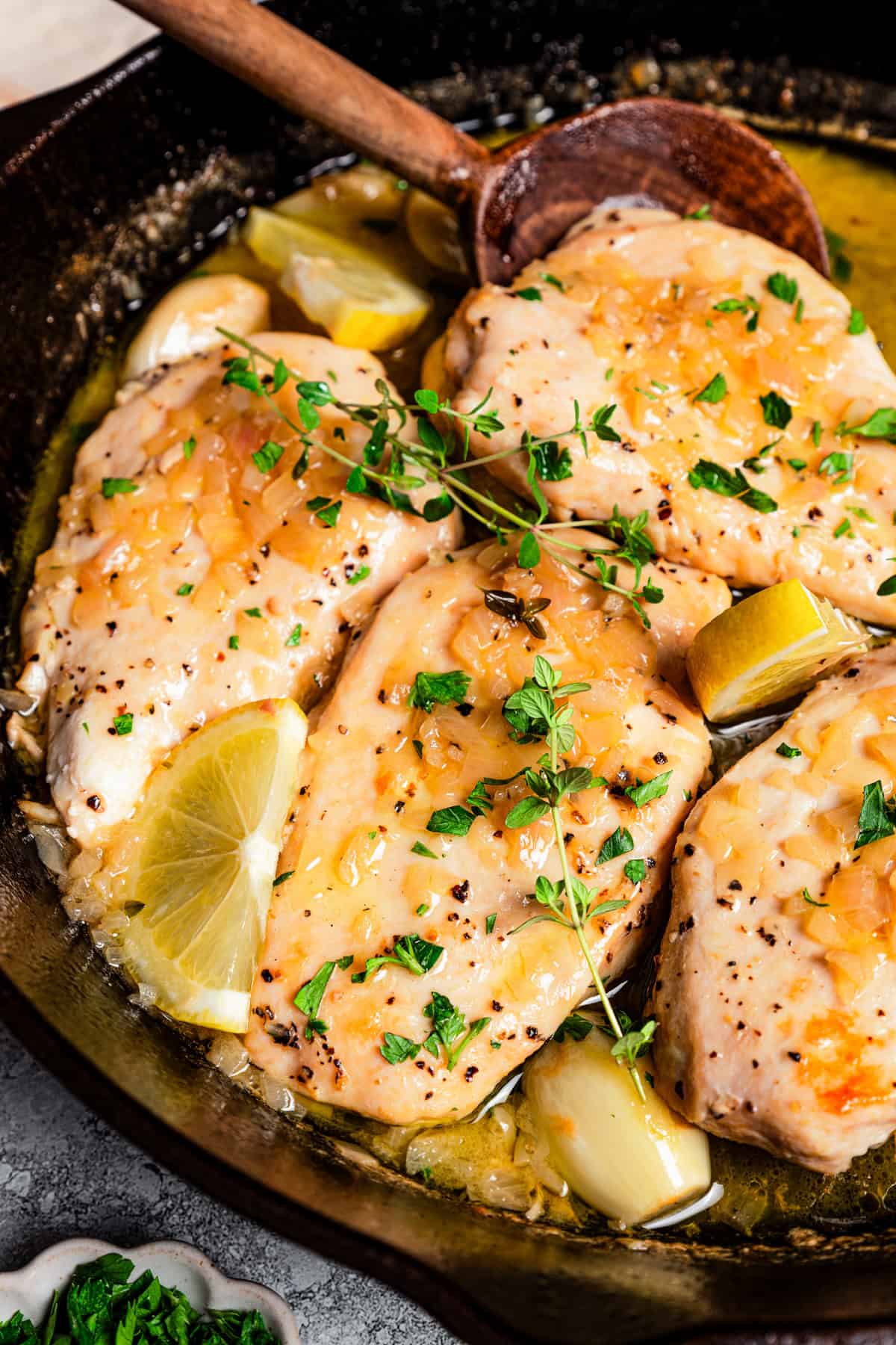 Cooking chicken paillard in a skillet, with a wooden spoon stirring through the sauce.