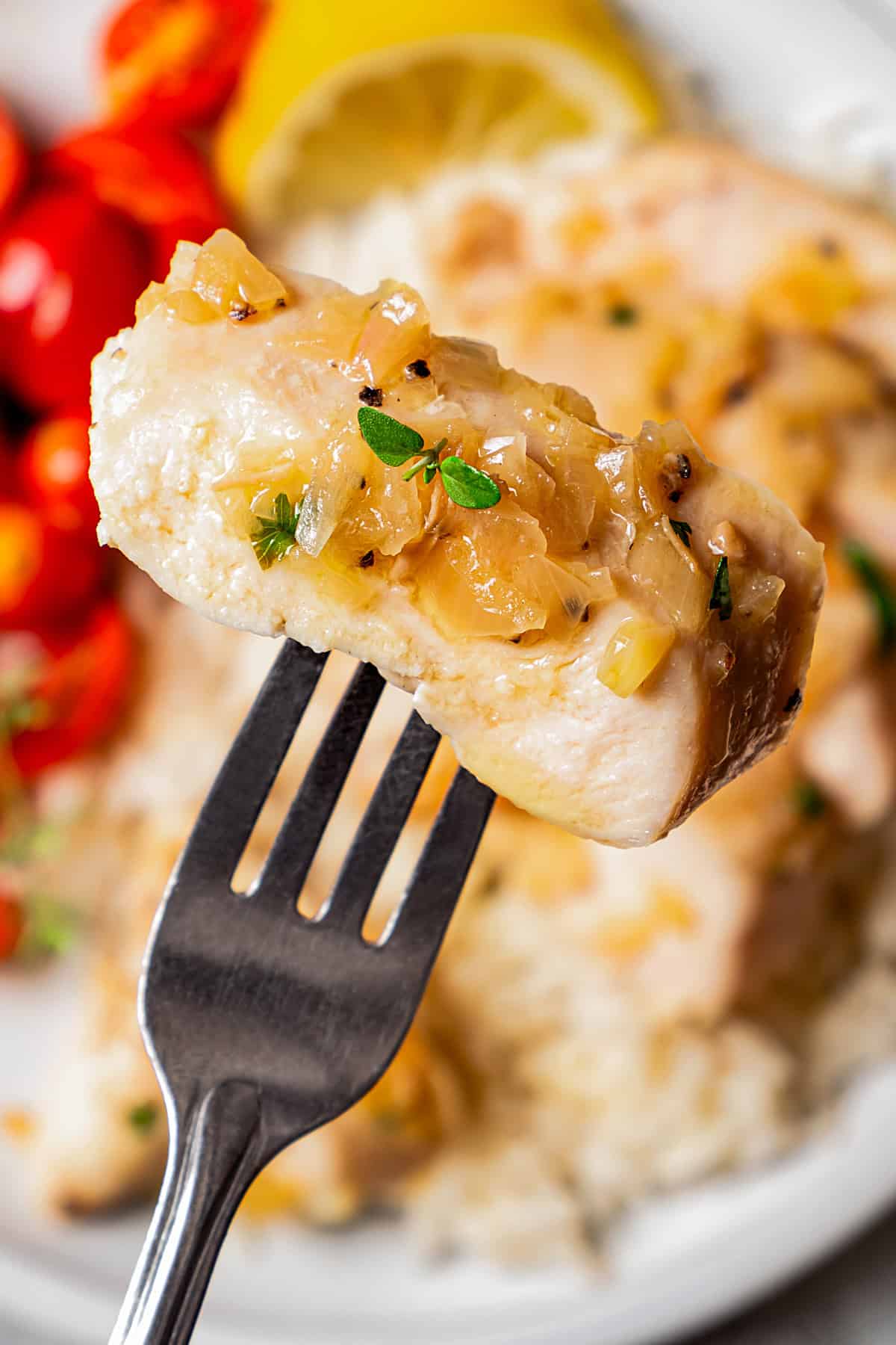 A fork holding up a piece of cooked chicken.