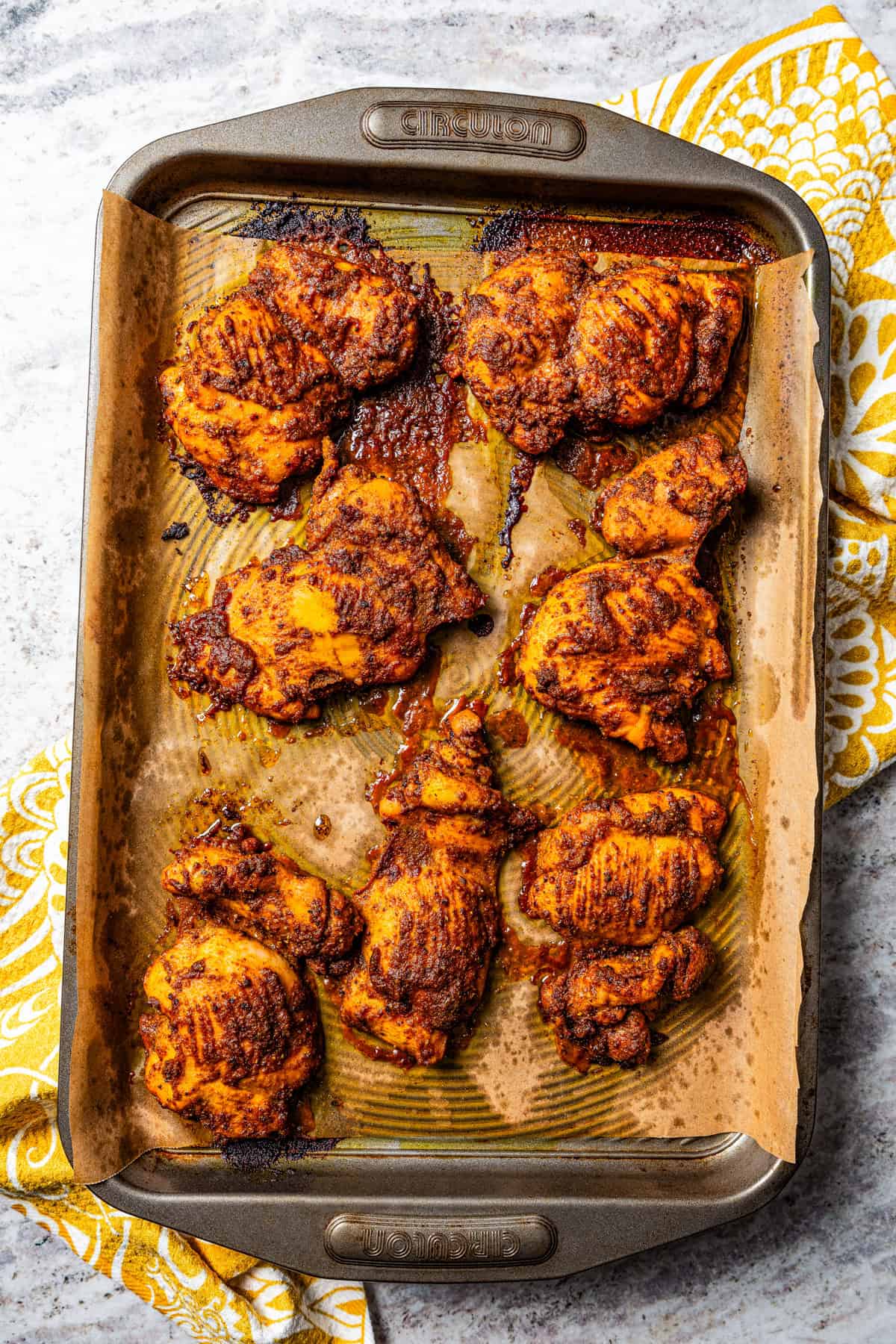 Seasoned baked chicken thighs arranged on a baking sheet.