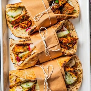 Chicken shawarma wrapped in pita bread, and the wraps are secured with brown paper and a kitchen string around them.