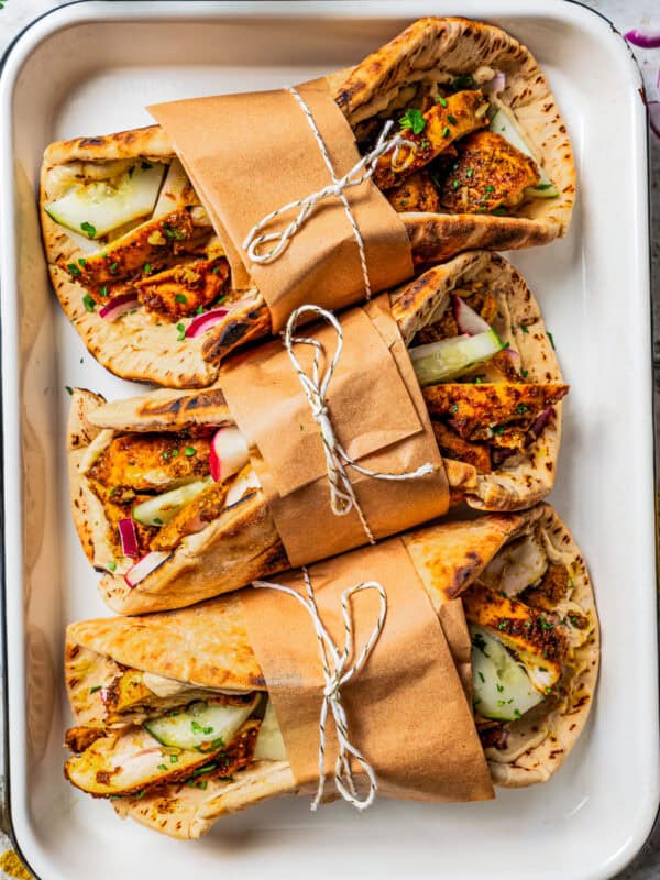 Chicken shawarma wrapped in pita bread, and the wraps are secured with brown paper and a kitchen string around them.