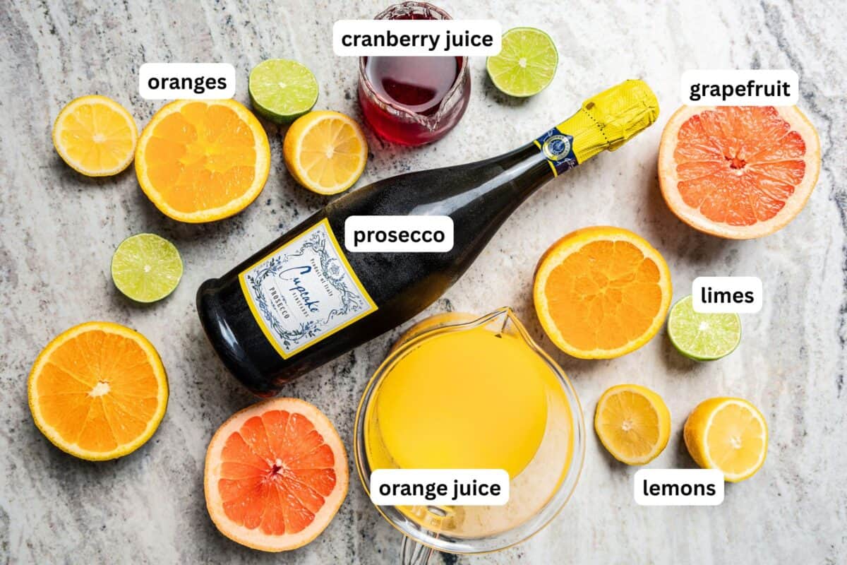 This classic mimosa recipe is made for a brunch crowd! Simple to make with orange juice and Prosecco, mixed in a pitcher with fresh citrus! Mimosa ingredients with text labels overlaying each ingredient.