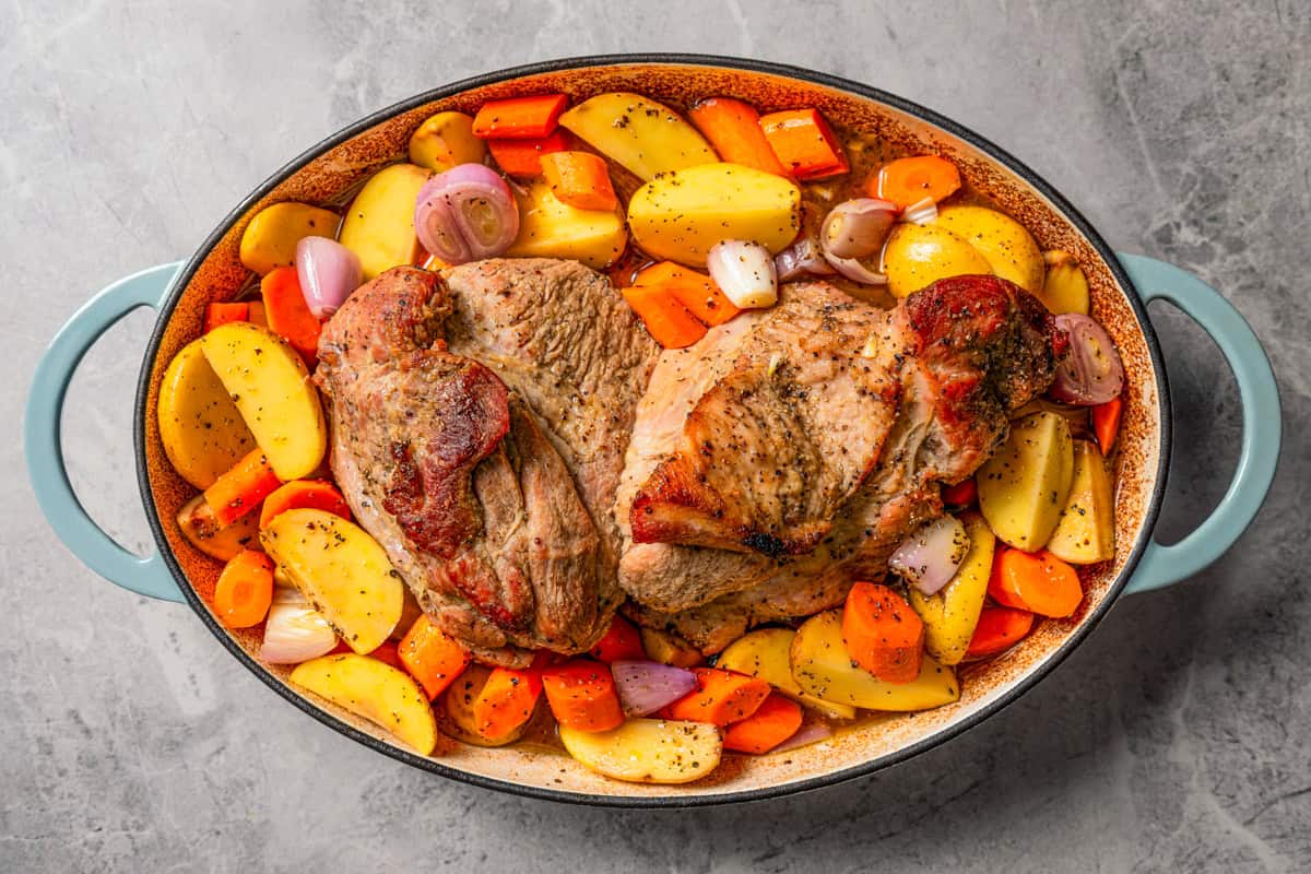 This pork roast recipe is a whole meal in one! With juicy seasoned pork shoulder slow-roasted with fresh citrus, carrots, potatoes, and herbs. Pork shoulder roast in a pot with carrots and potatoes.