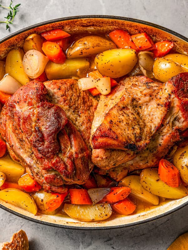 Pork shoulder roast in a pot with roasted carrots and potatoes.