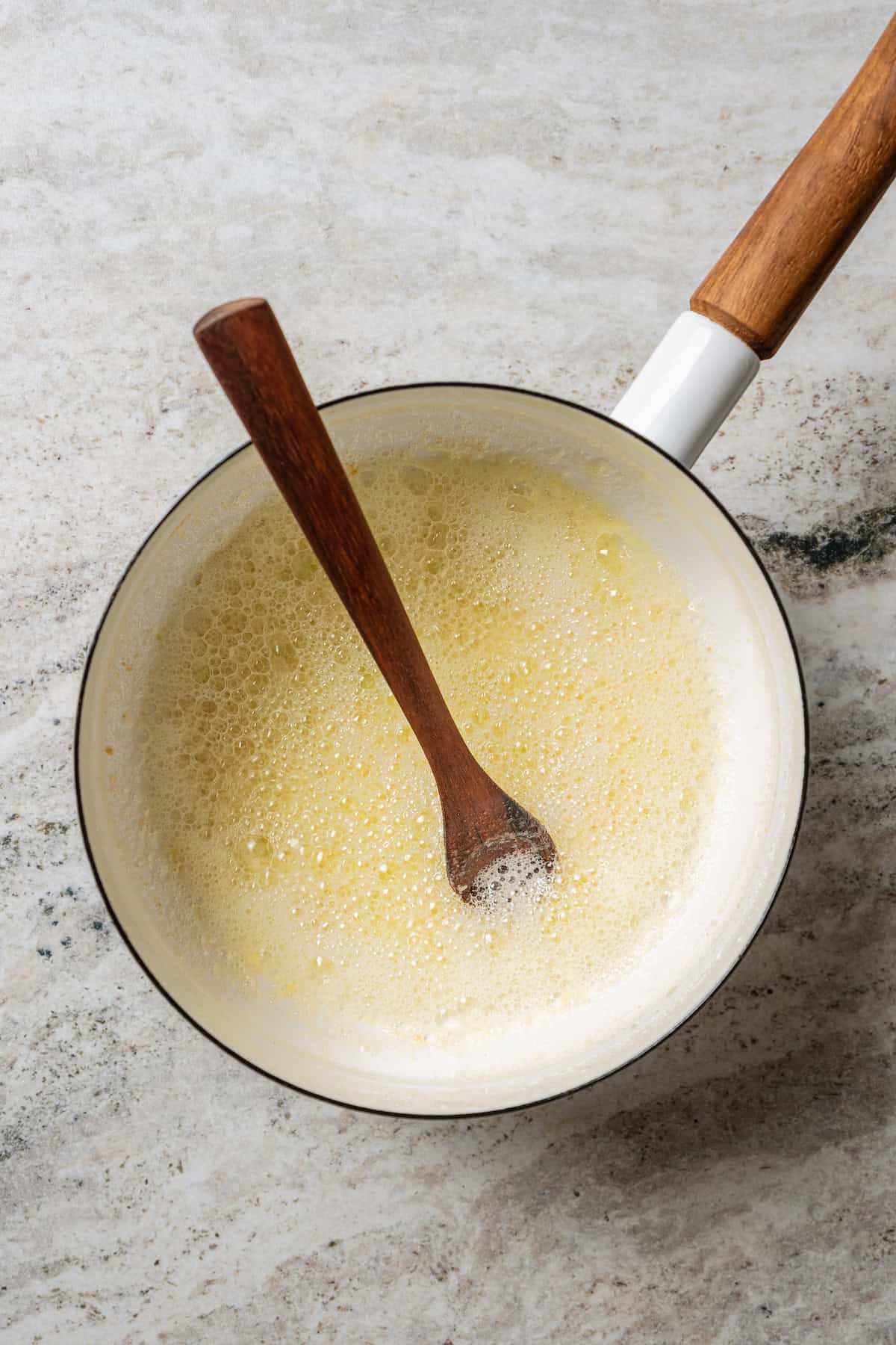 Garlic butter in a saucepan with a wooden spoon.