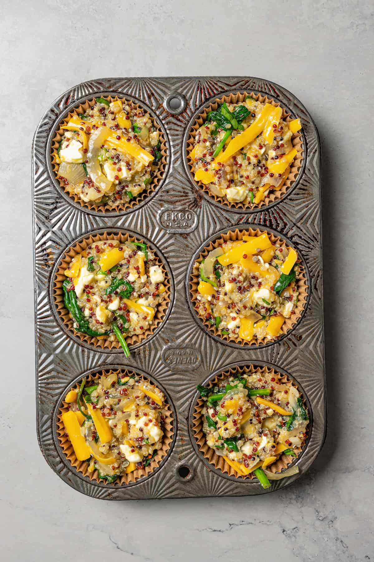 Overhead view of unbaked quiche muffin batter in a muffin tin.