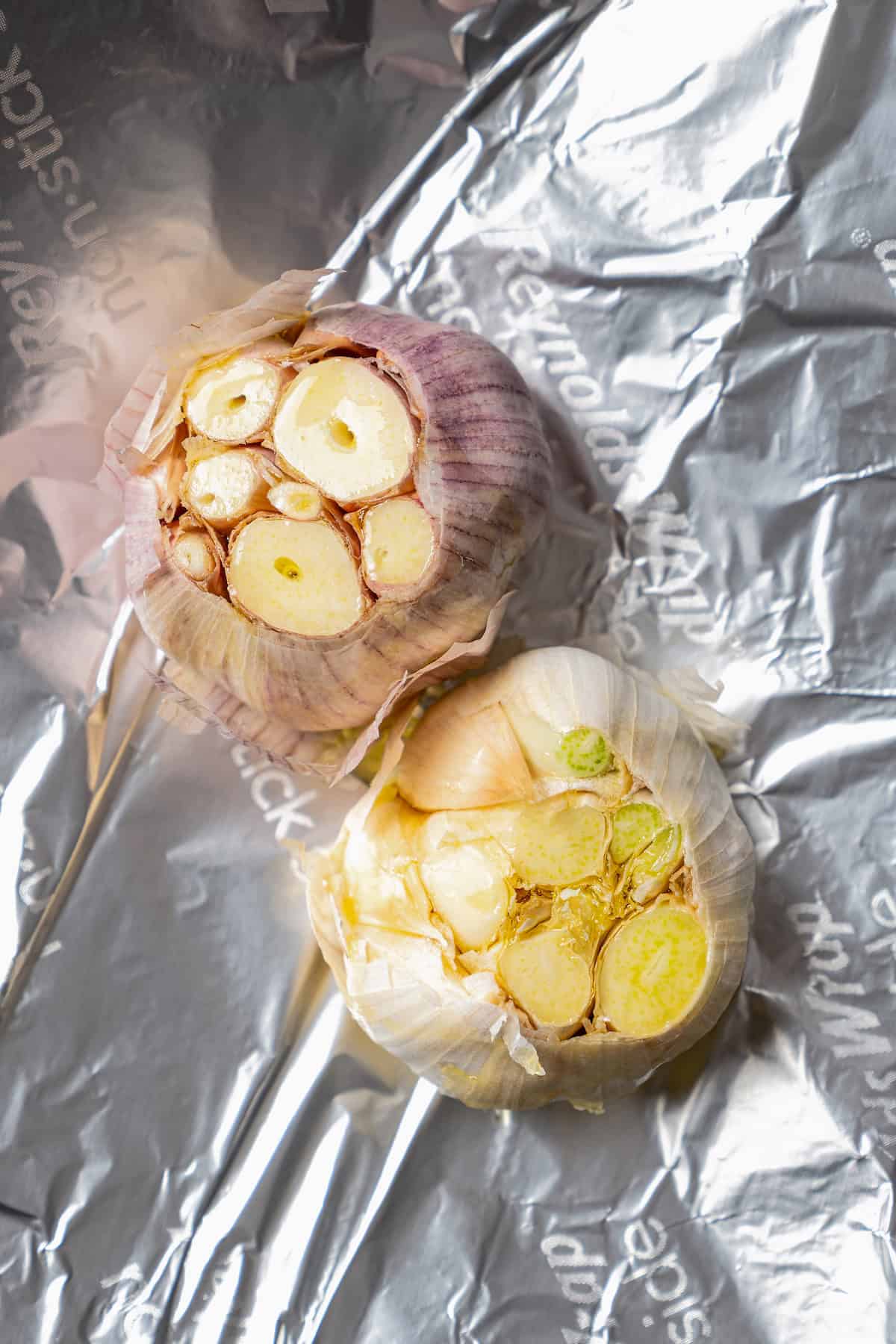 Close up of two whole garlic bulbs on a sheet of foil,