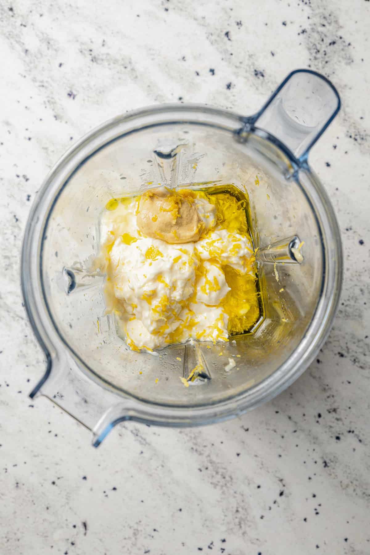 Overhead view of roasted garlic and aioli ingredients combined in a blender.