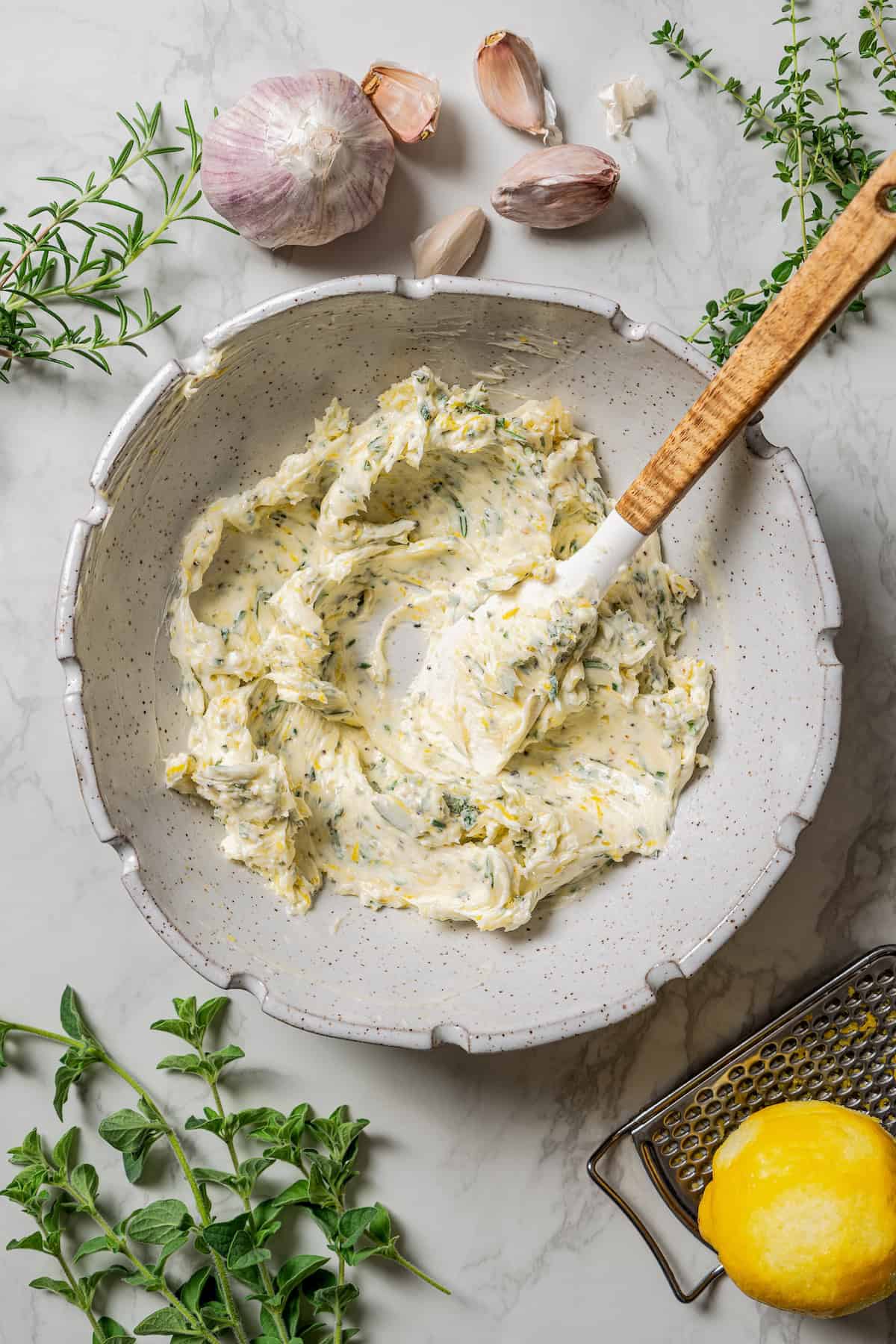 Herb compound butter combined in a bowl with a spoon.