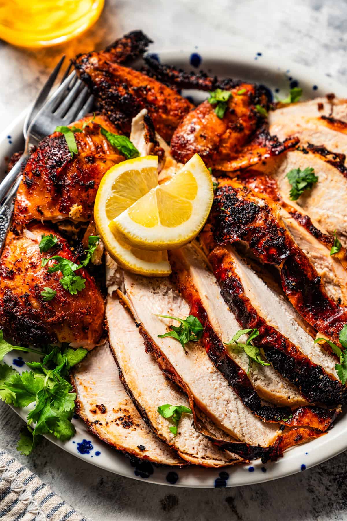 Close-up of sliced chicken on a platter garnished with lemon wedges.