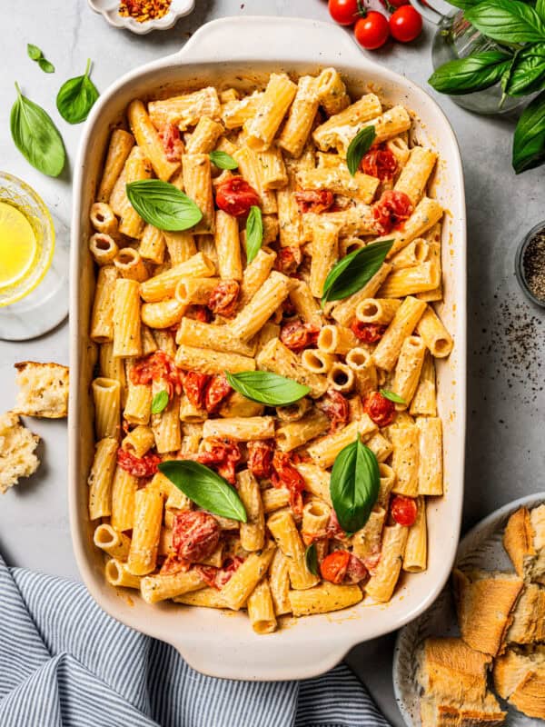 Overhead view of baked Boursin pasta in a ceramic baking dish, surrounded by pasta ingredients.