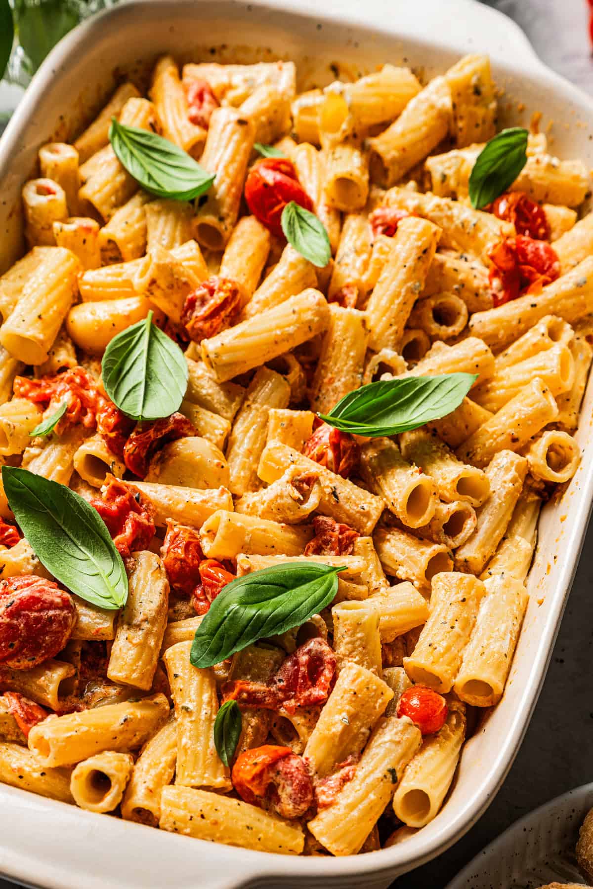 Baked Boursin pasta in a ceramic baking dish garnished with fresh basil leaves.